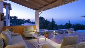 A covered outdoor seating area with a view of the sea, a stone wall, and a potted plant. - Villa Borsa: Secluded Retreat with Sea Views, Gym and near famous beaches (Lefkada)