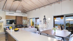 A modern kitchen with a large island, dining area with chairs, and a view of the outdoors. - Villa Borsa: Secluded Retreat with Sea Views, Gym and near famous beaches (Lefkada)