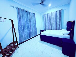 A bedroom with a bed, curtains, a ceiling fan, and a wooden ladder.