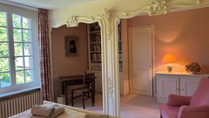 Une chambre à coucher comprenant un lit, une chaise, un bureau, une bibliothèque et une porte donnant sur une autre pièce.