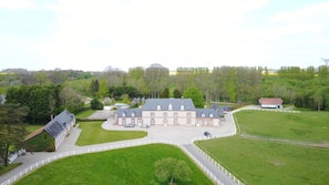 Un grand bâtiment à plusieurs étages, doté d’une façade symétrique, entouré de vastes pelouses verdoyantes et d’une clôture blanche.