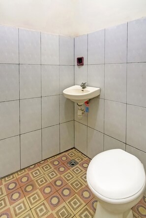 A bathroom with a toilet, a sink, and patterned floor tiles.