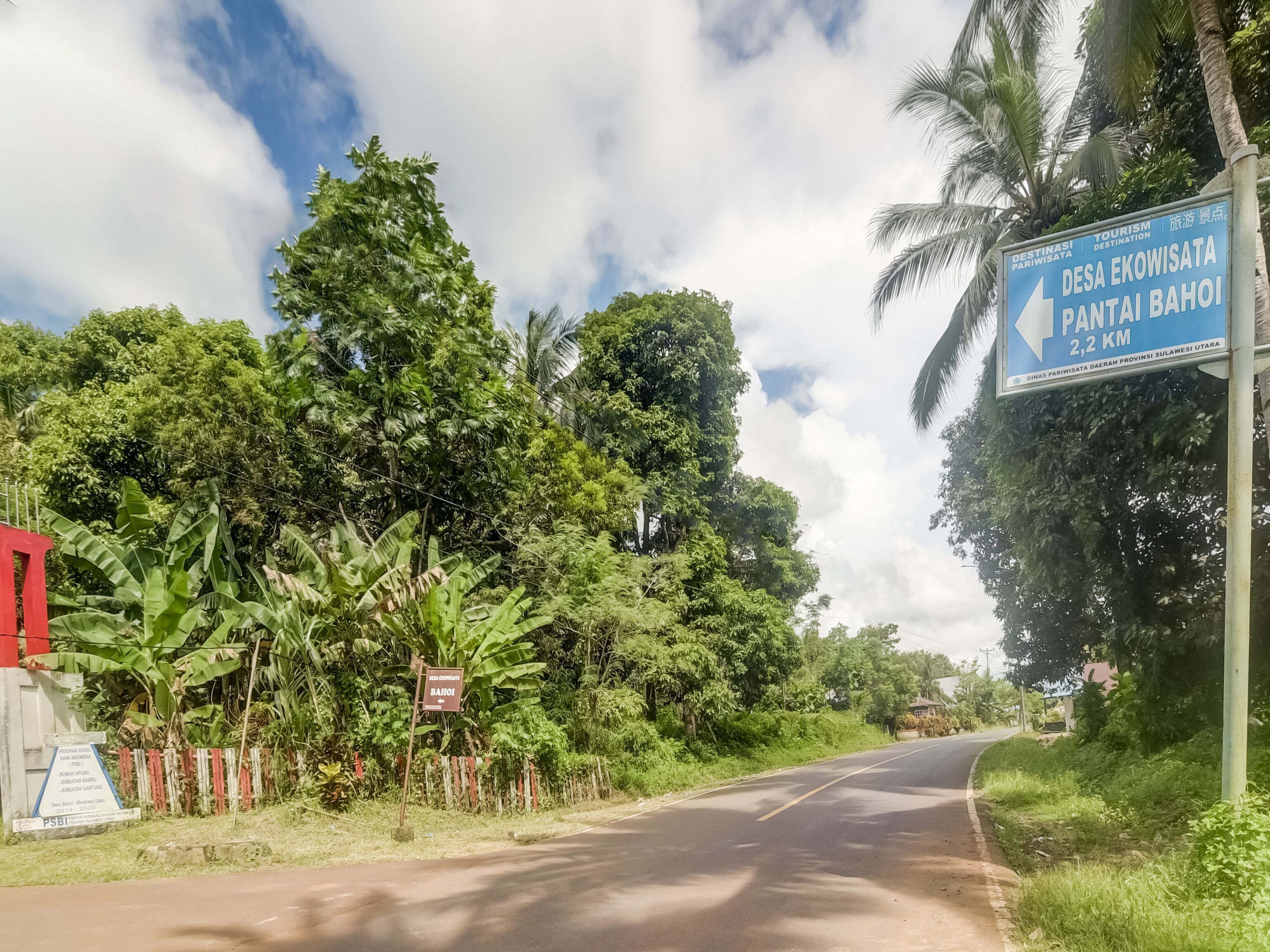 Un panneau de signalisation indiquant une destination, entouré d’une végétation luxuriante et sous un ciel dégagé.