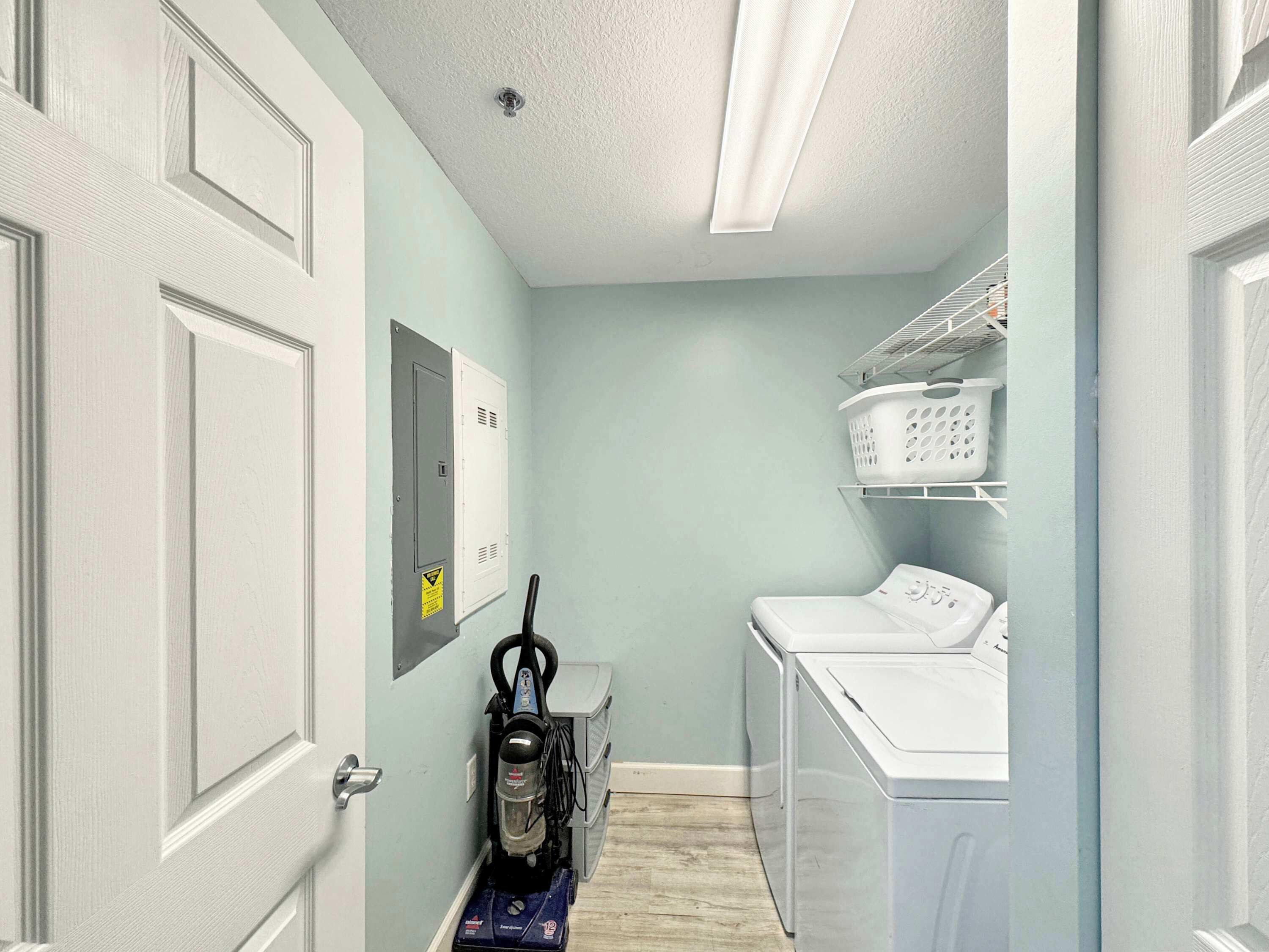 A laundry room with a washing machine, dryer, and a vacuum cleaner.