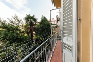 A balcony with a metal railing, a tiled floor, and a view of greenery and buildings in the background. - Apartment just a few meters from the historic district of San Frediano in Florence! (Firenze)