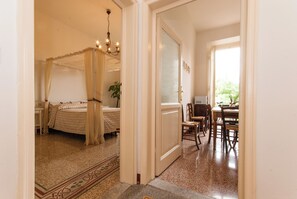 A bedroom with a four-poster bed, a chandelier, and a dining area with wooden furniture. - Apartment just a few meters from the historic district of San Frediano in Florence! (Firenze)