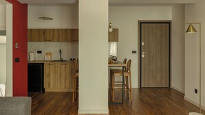 Een moderne keuken met houten kastjes, een eettafel met stoelen, een koelkast en een hanglamp.