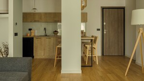 Een moderne keuken met houten kastjes, een eethoek met tafel en stoelen, een bank en een lamp.