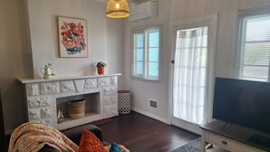 A living room with a fireplace, a television, and a sofa with cushions. - South Bunbury Beach Shack (South Bunbury)