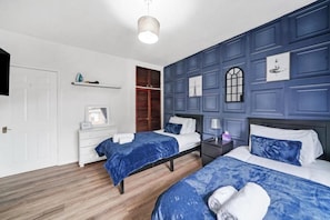 A bedroom with two beds, a white dresser, a mirror, a window with a view, and a wall-mounted shelf. - Cosy 2 Bed 5 Guests Garden Parking-wifi & Netflix (London)