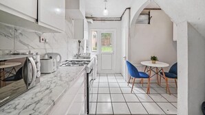 A modern kitchen with a marble countertop, a gas stove, and a view to the outside. - Cosy 2 Bed 5 Guests Garden Parking-wifi & Netflix (London)