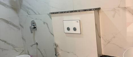A bathroom with a toilet, shower, and sink.