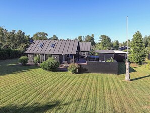 A modern house with a sloped roof, a covered patio, and a well-maintained lawn. - 4 Star Holiday Home in Vaeggerlose (Vaeggerlose)