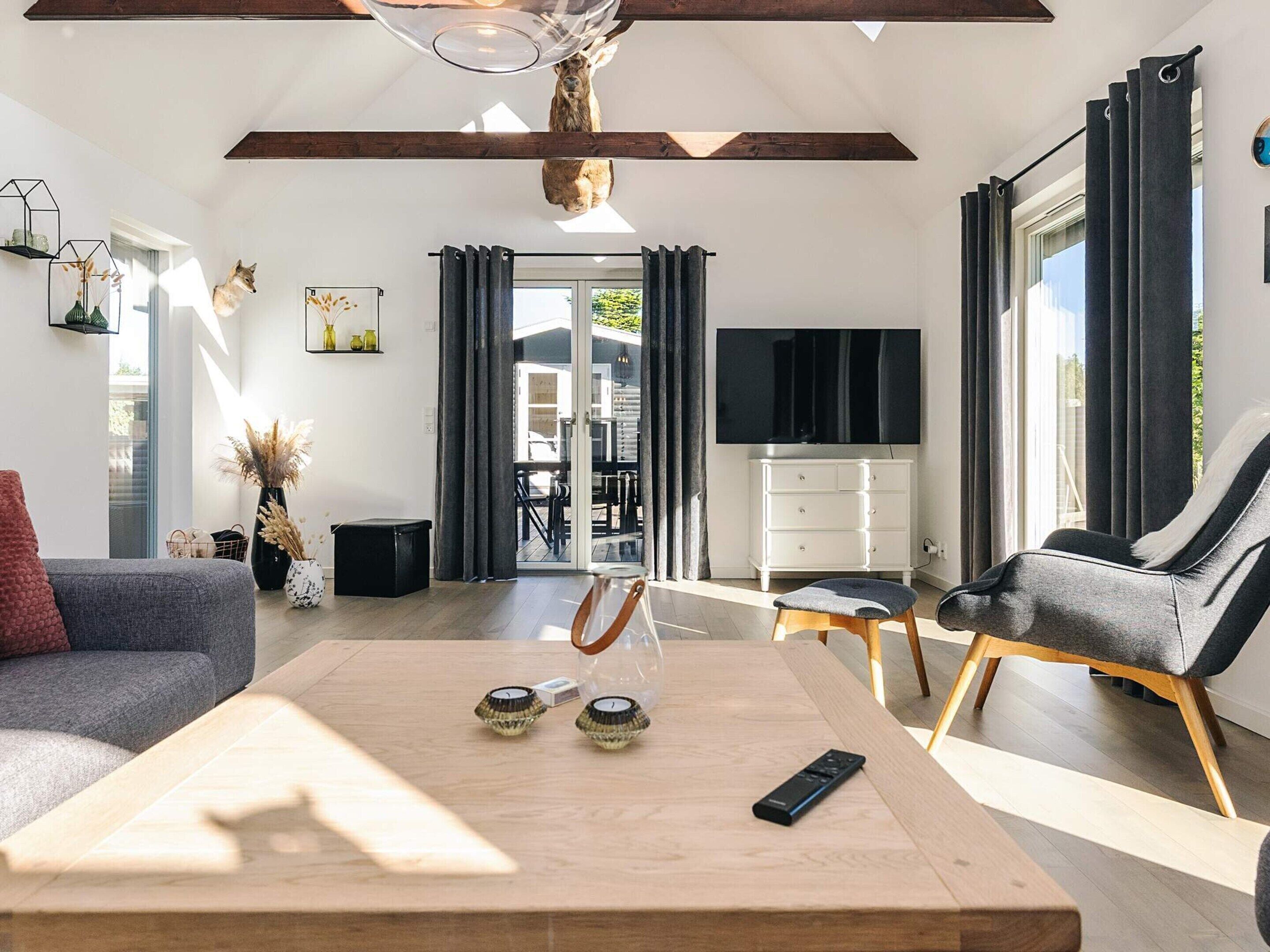 Un salon moderne avec une table basse en bois, un canapé, un téléviseur et un coin repas comprenant une table et des chaises.