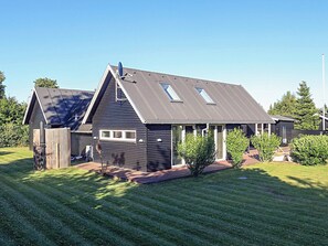 Een modern huis met twee verdiepingen, een schuin dak, omheinde tuin en een kleine siertuin.