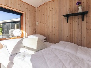 Een slaapkamer met een bed, een raam en een houten wand.