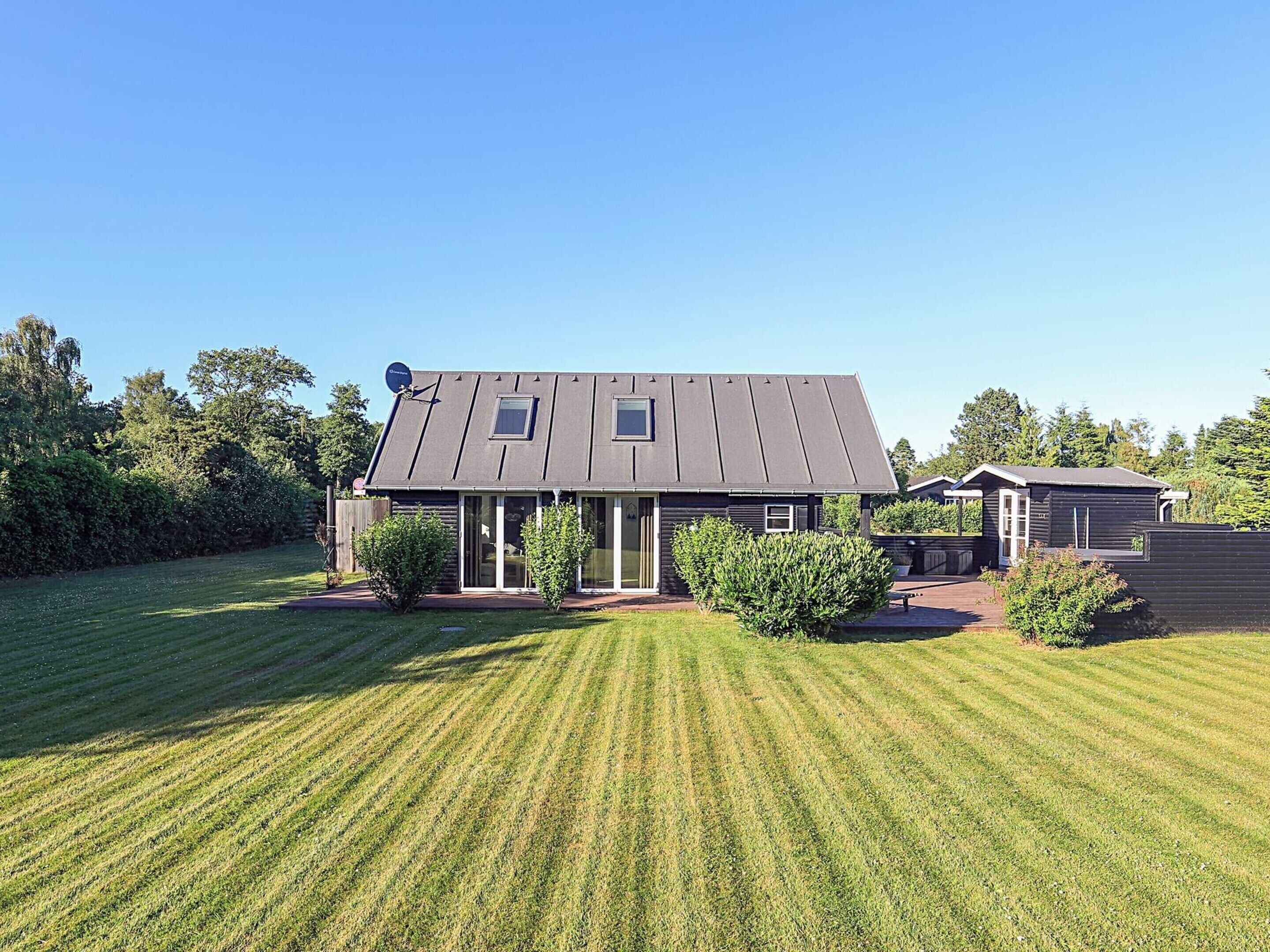 A house with a sloped roof, a satellite dish, and a well-maintained lawn.