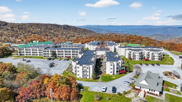 A multi-story hotel with a parking lot, surrounded by autumn foliage and mountains. - Beech Mountain Escape | Pool, Fireplace, Near Ski (Beech Mountain)