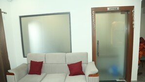 A room with a sofa, a mirror, and an office door. - Hotel Akash Palace  (Kotda Sangani)