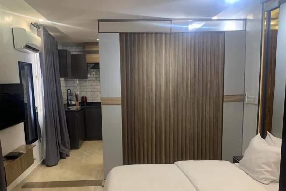 Une chambre d’hôtel équipée d’un lit, d’une télévision, d’une kitchenette et d’une salle de bain.