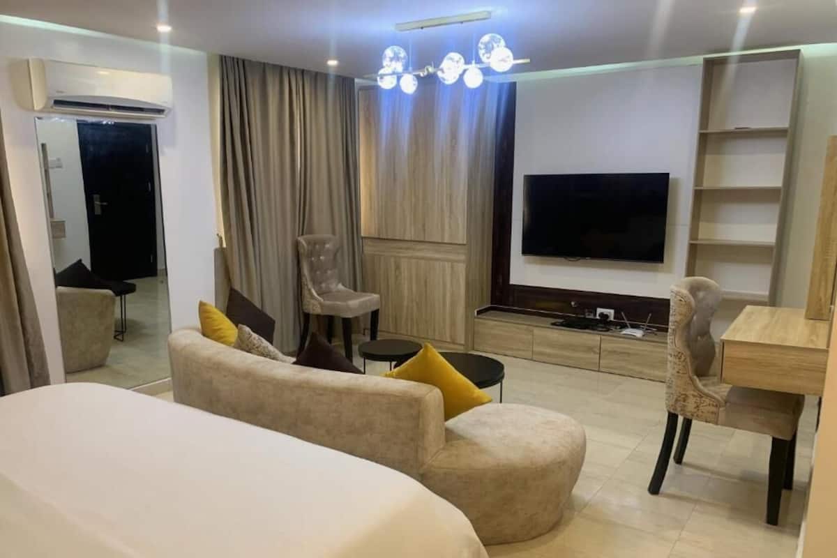 Une chambre d’hôtel équipée d’un lit, d’un canapé, d’une chaise, d’un bureau, d’une télévision et d’une armoire.