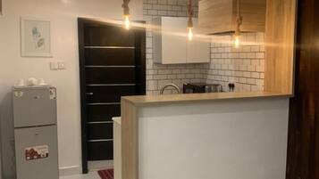 Una cocina moderna con una isla central, iluminación colgante y un horno empotrado.