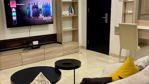 Un soggiorno moderno con una TV a schermo piatto, un divano, un tavolino e una libreria.