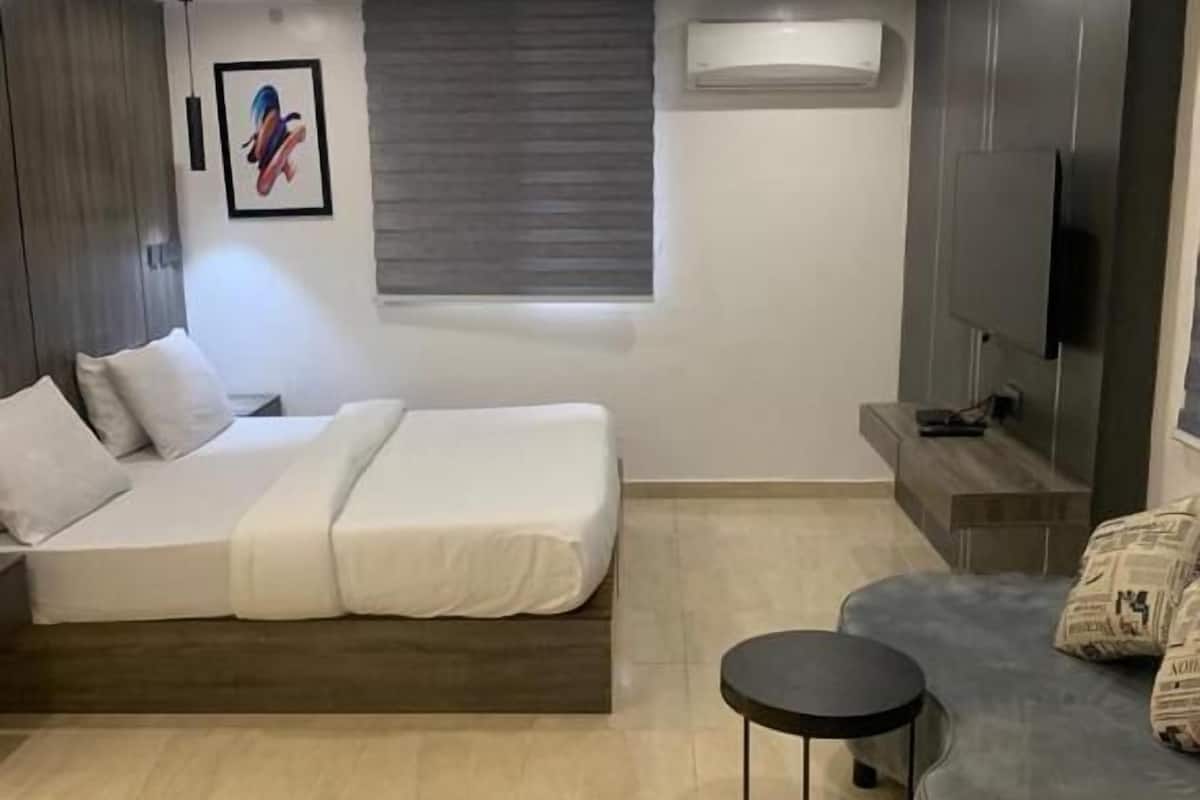 Une chambre moderne avec un lit, une petite table ronde, un canapé et un téléviseur.