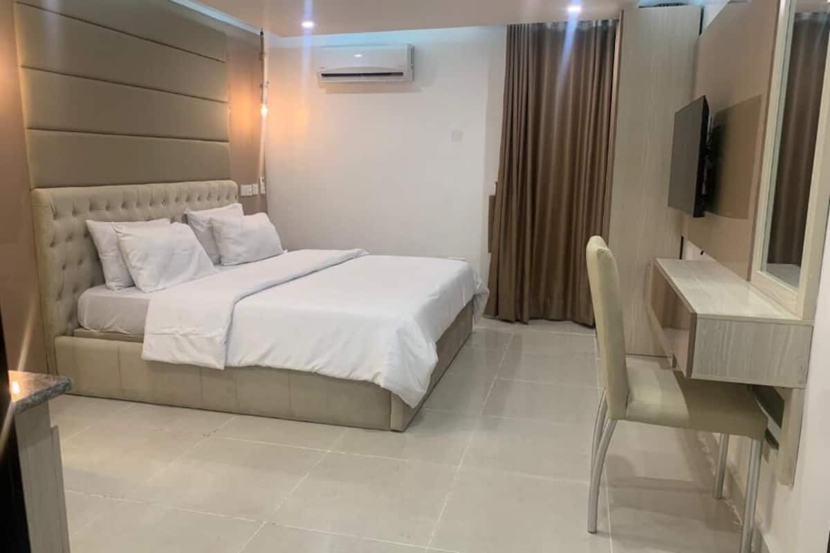 Une chambre d’hôtel équipée d’un lit, d’un bureau, d’une chaise, d’un climatiseur et d’un téléviseur.