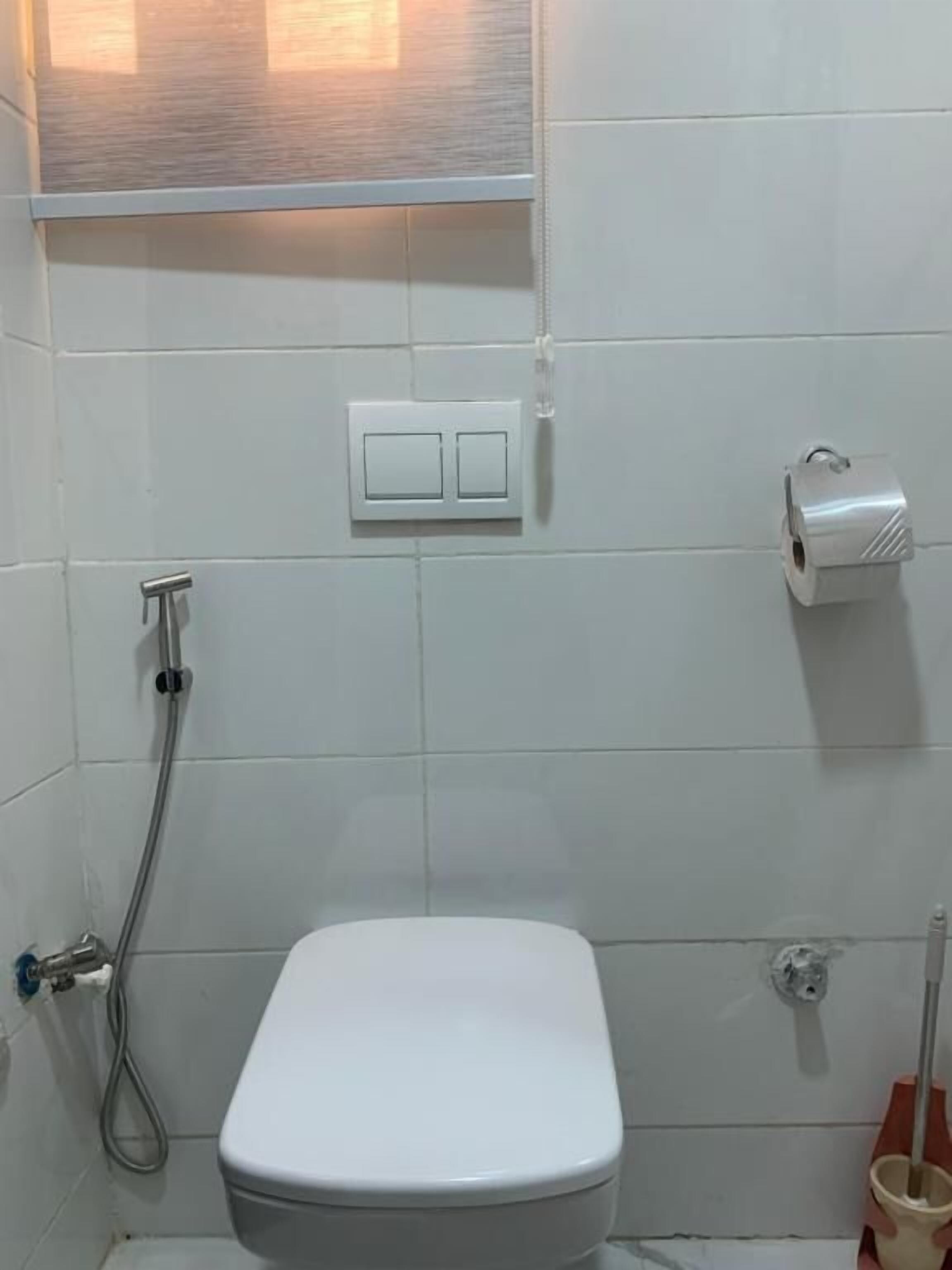 A bathroom with a toilet, a shower, a hand dryer, and a towel rack.