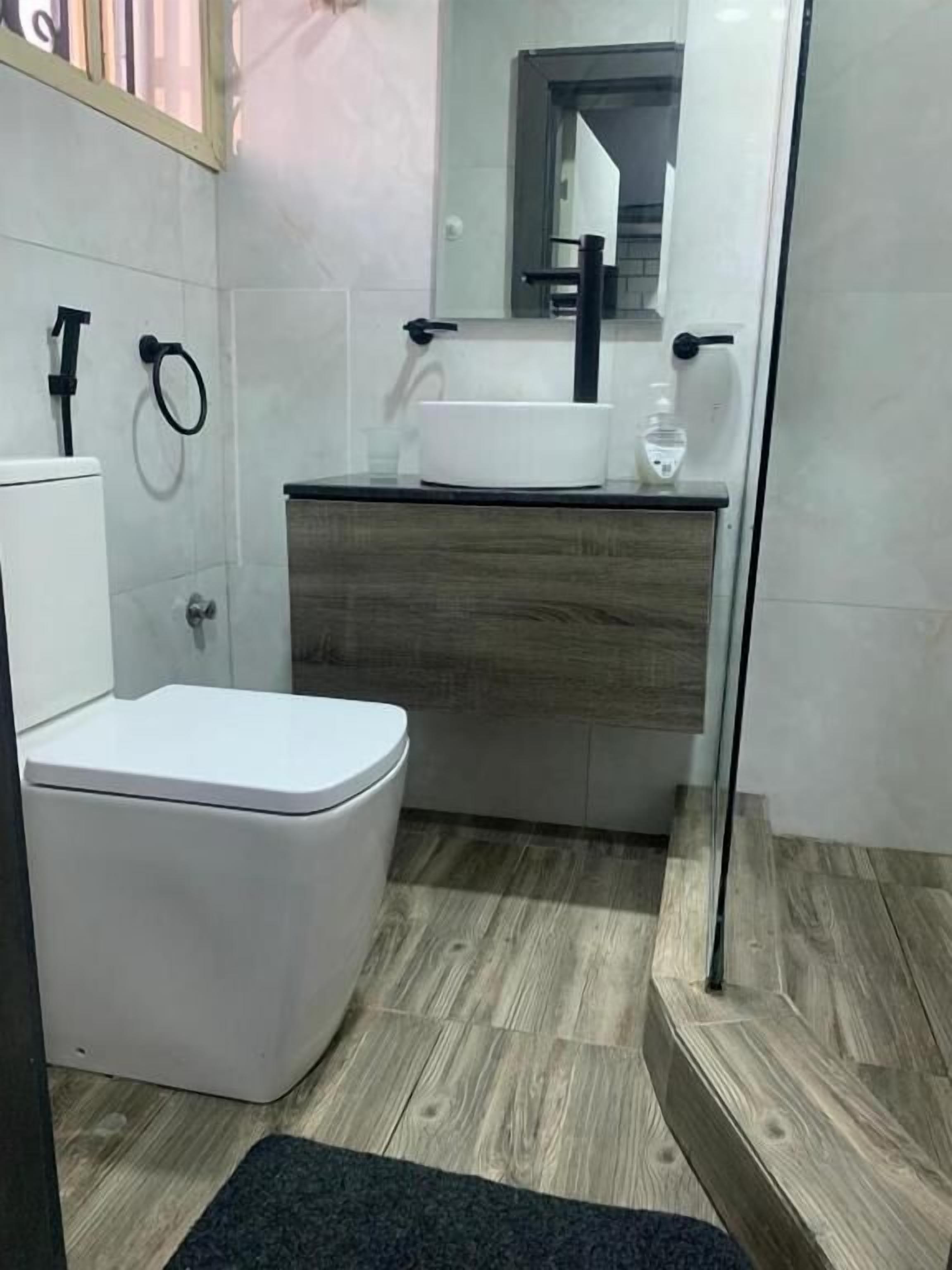 A modern bathroom with a toilet, sink, and mirror.