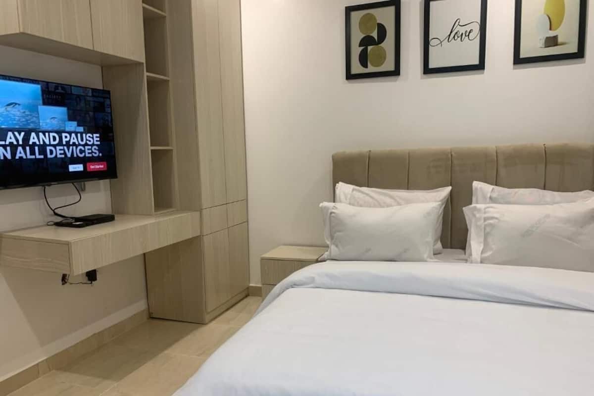Une chambre à coucher avec un lit, une télévision, une table de chevet et des œuvres d’art murales.