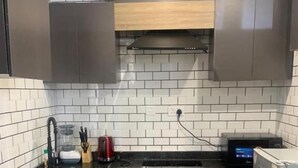 Una cucina compatta con piano di lavoro nero, lavello in acciaio inossidabile e forno integrato.