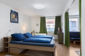 A bedroom with a bed, bedside table, lamp, and a window with curtains.