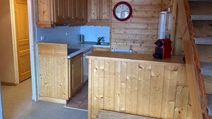 Una cocina con armarios de madera, un reloj y un electrodoméstico rojo.