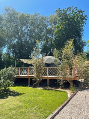 A wooden deck with a pergola, surrounded by lush greenery and trees. - Nature Dome & Jacuzzi at Blue Grass Ranch (Bischoffsheim)