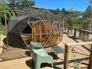 A geodesic dome tent with a patterned exterior, a small table, and a chair on a wooden deck. - Nature Dome & Jacuzzi at Blue Grass Ranch (Bischoffsheim)