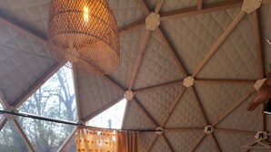 A room with a bed, a dining table with chairs, a hanging light fixture, and a view through a window. - Nature Dome & Jacuzzi at Blue Grass Ranch (Bischoffsheim)