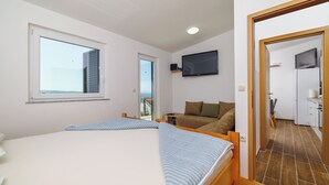 Ein Schlafzimmer mit zwei Betten, einem Fernseher, einem Sofa und Meerblick.