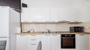 Eine moderne Küche mit weißen Schränken, einer Holz Arbeitsplatte, einem eingebauten Backofen und einer Mikrowelle.