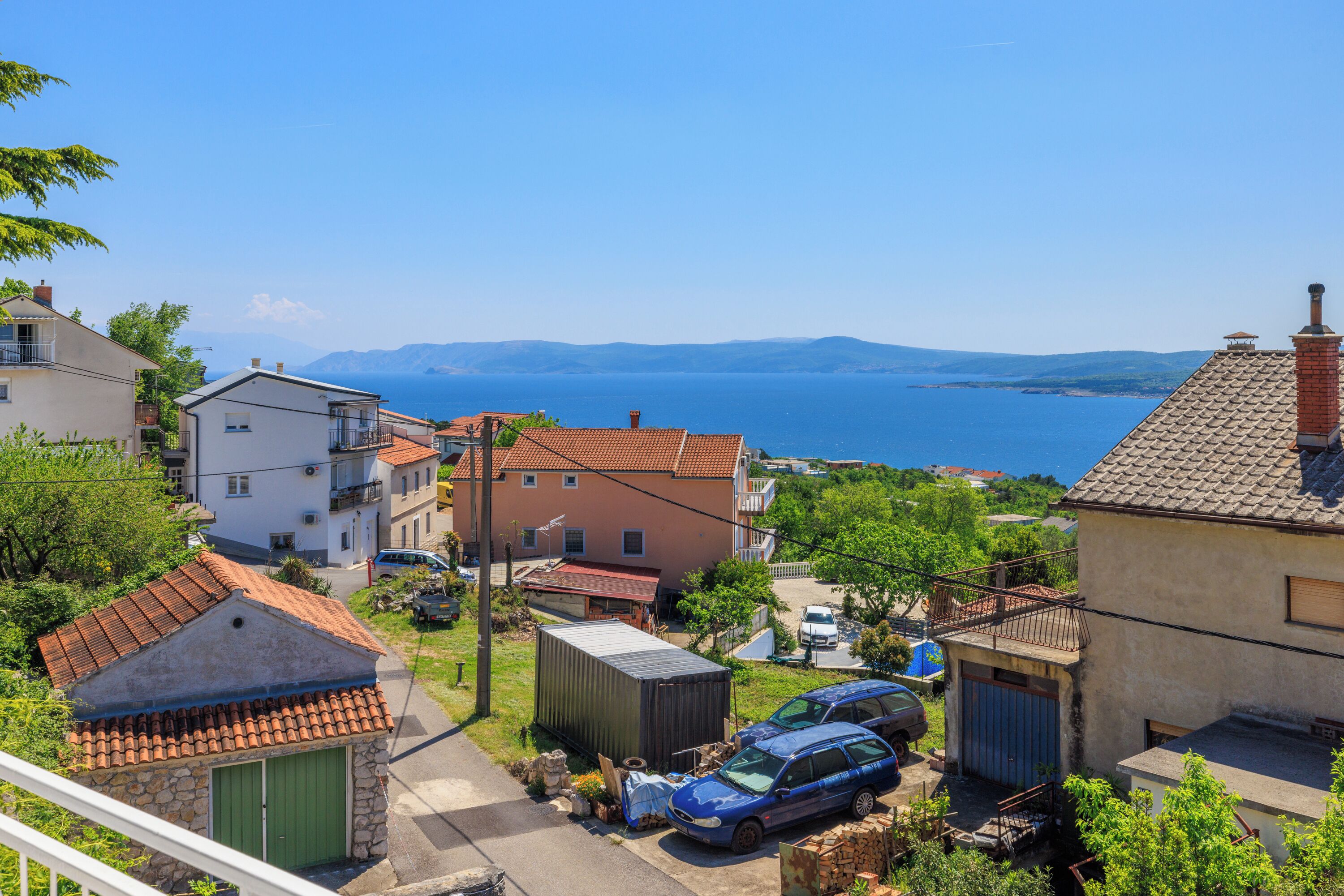Un quartier résidentiel situé sur la côte, avec des maisons, un ciel bleu dégagé et une vue sur la mer.