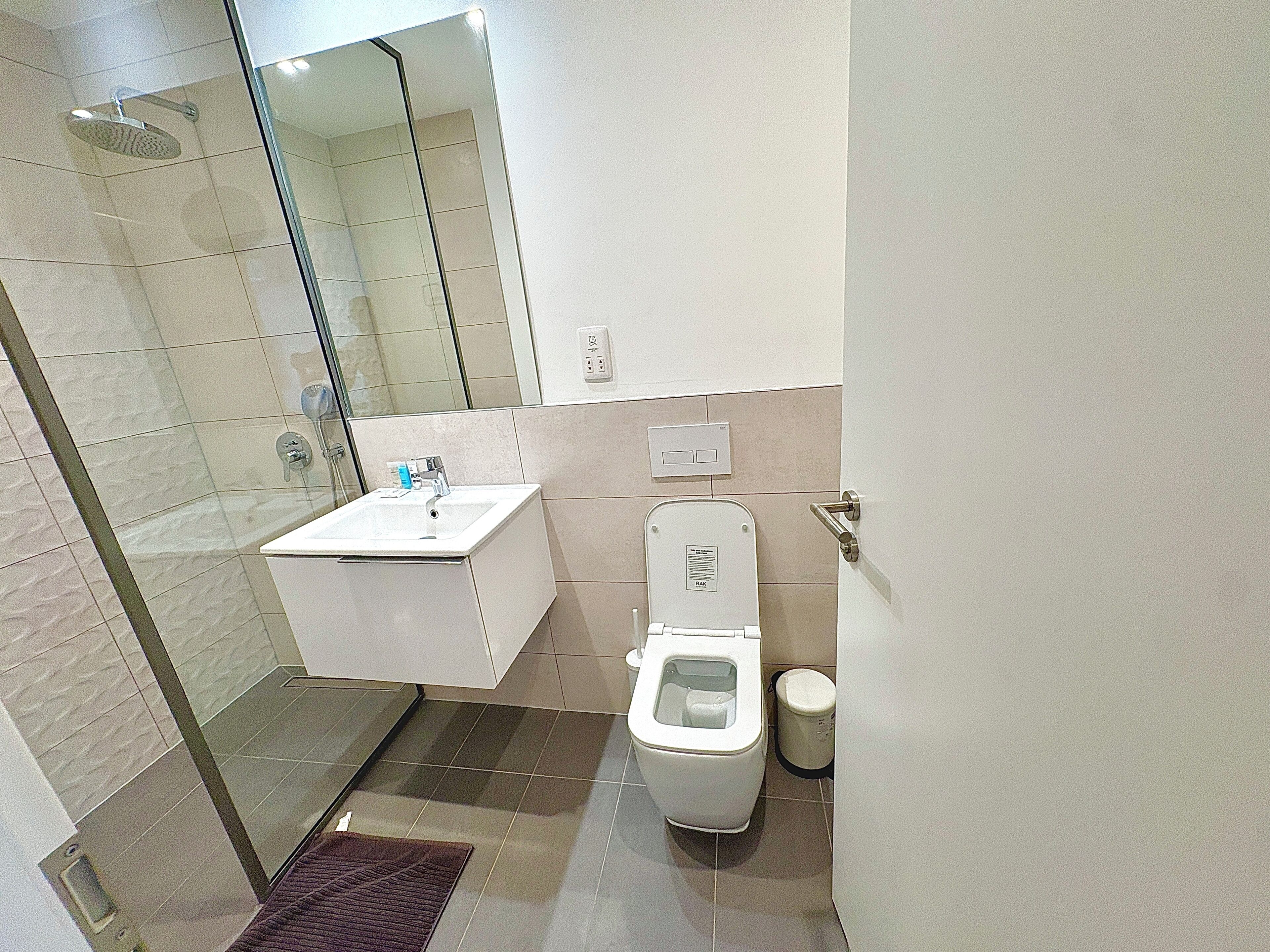 A bathroom with a shower, toilet, and sink.