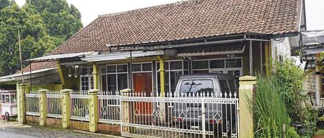 A building with a tiled roof, a fenced area, and a parked vehicle.