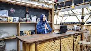 Una cafetería rústica con interior de bambú, una barra de madera y diversos artículos relacionados con el café a la vista.
