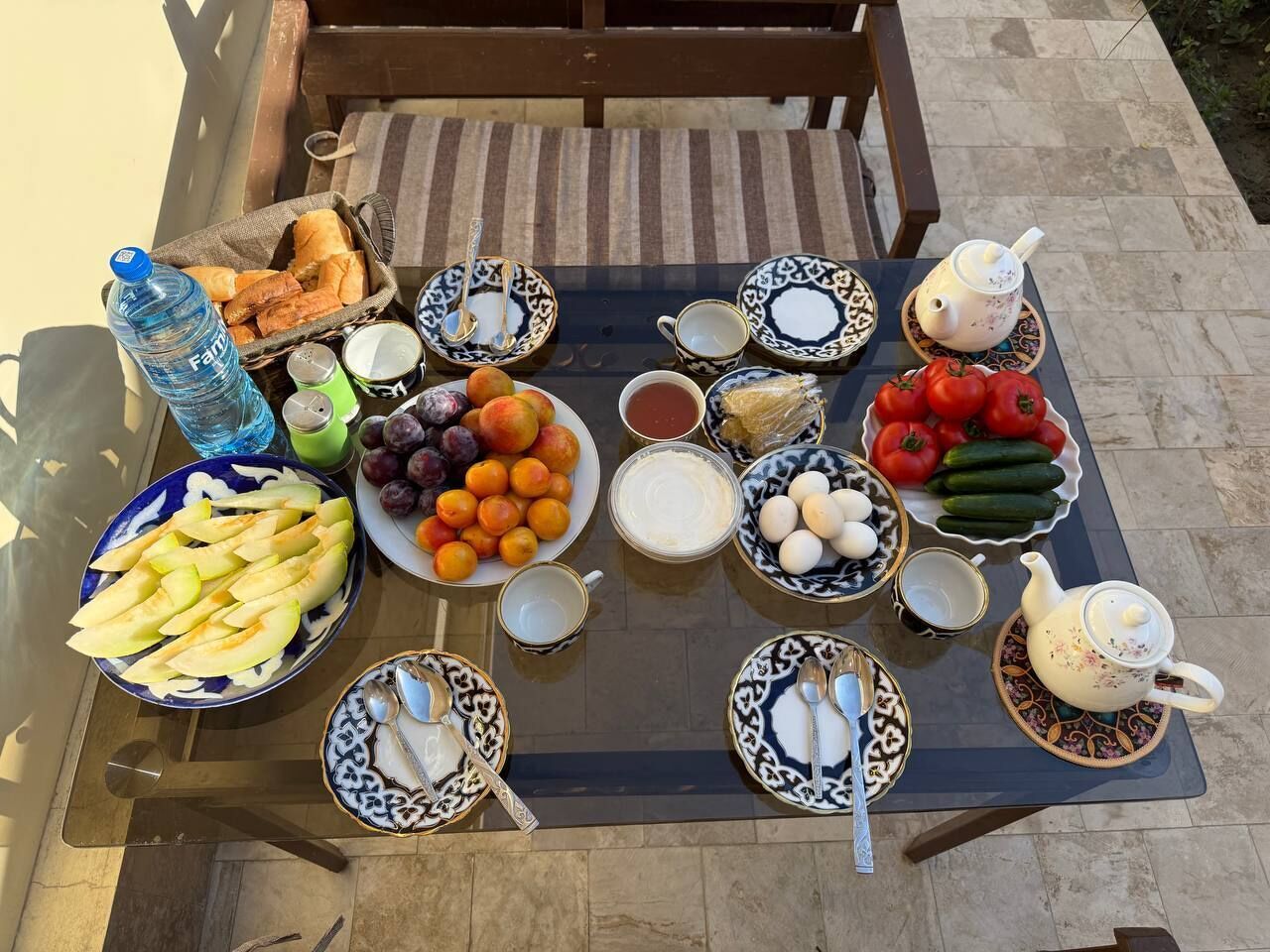 Una mesa dispuesta con diferentes alimentos y utensilios, incluyendo frutas, verduras, pan y teteras.