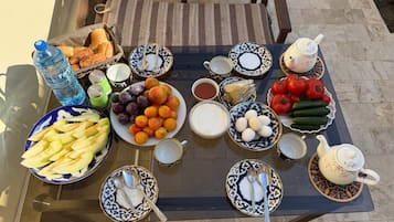 Una mesa dispuesta con diferentes alimentos y utensilios, incluyendo frutas, verduras, pan y teteras.
