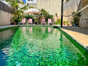 A swimming pool with clear water, surrounded by lounge chairs and potted plants. - A Charming terraced house in the heart of Pollensa, in the Escaleras del Calvario area, with a large swimming pool. (Pollensa / Pollença)