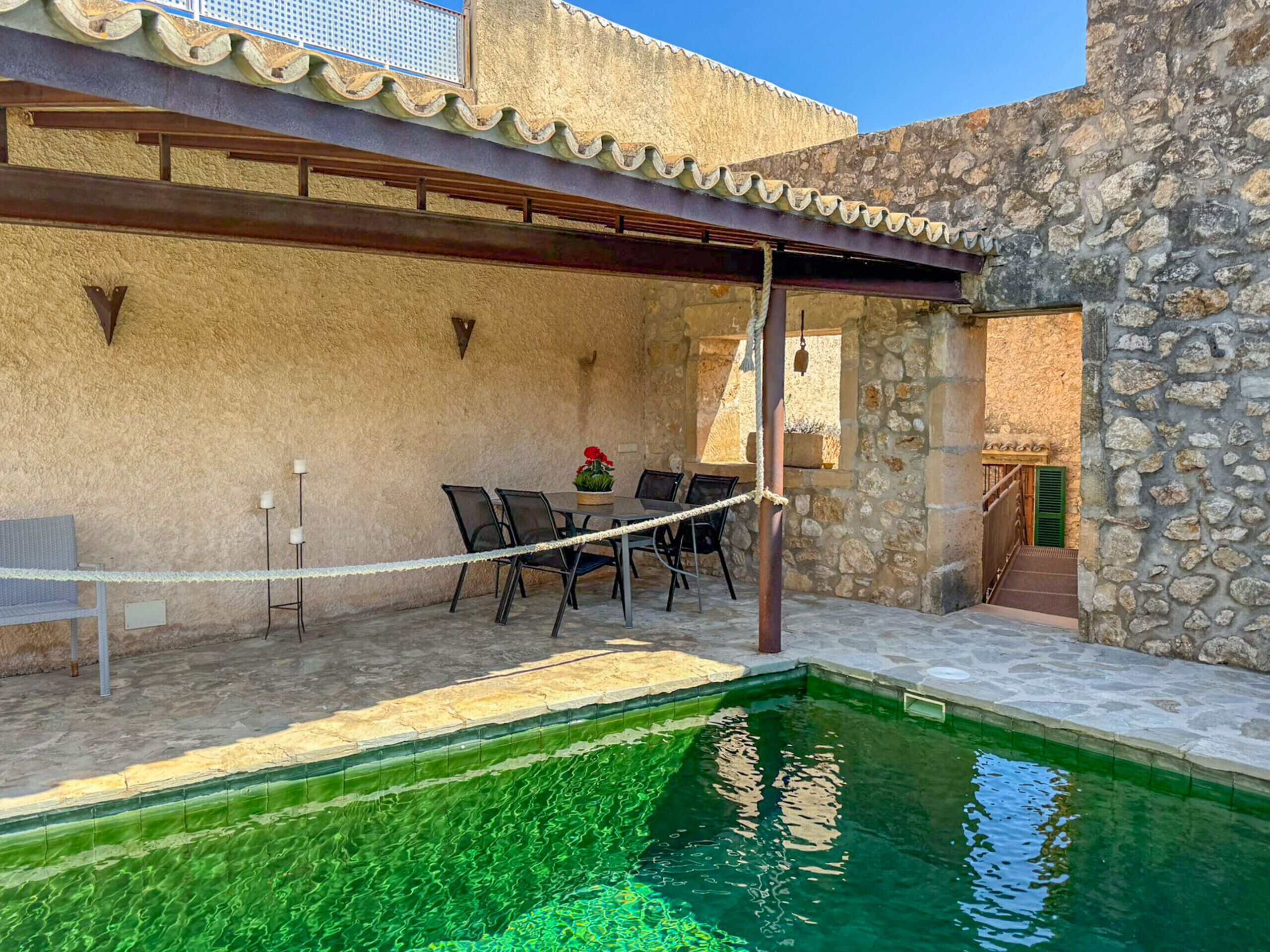 Un espace piscine agrémenté d’un mur en pierre, d’un coin salon abrité et d’un escalier menant à un niveau supérieur.