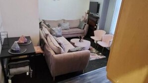 A compact living space with a sofa, a small table, a television, and a chair. - glamsflat troccadero (Wolverhampton)