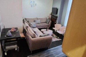 Ein gemütlicher Wohnbereich mit einer Couch, einem kleinen Tisch, einem Fernseher und einem Sessel.